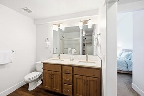 Ein modernes Badezimmer mit einem Waschbecken-Doppelwaschplatz, einer Toilette und einem großen Spiegel.