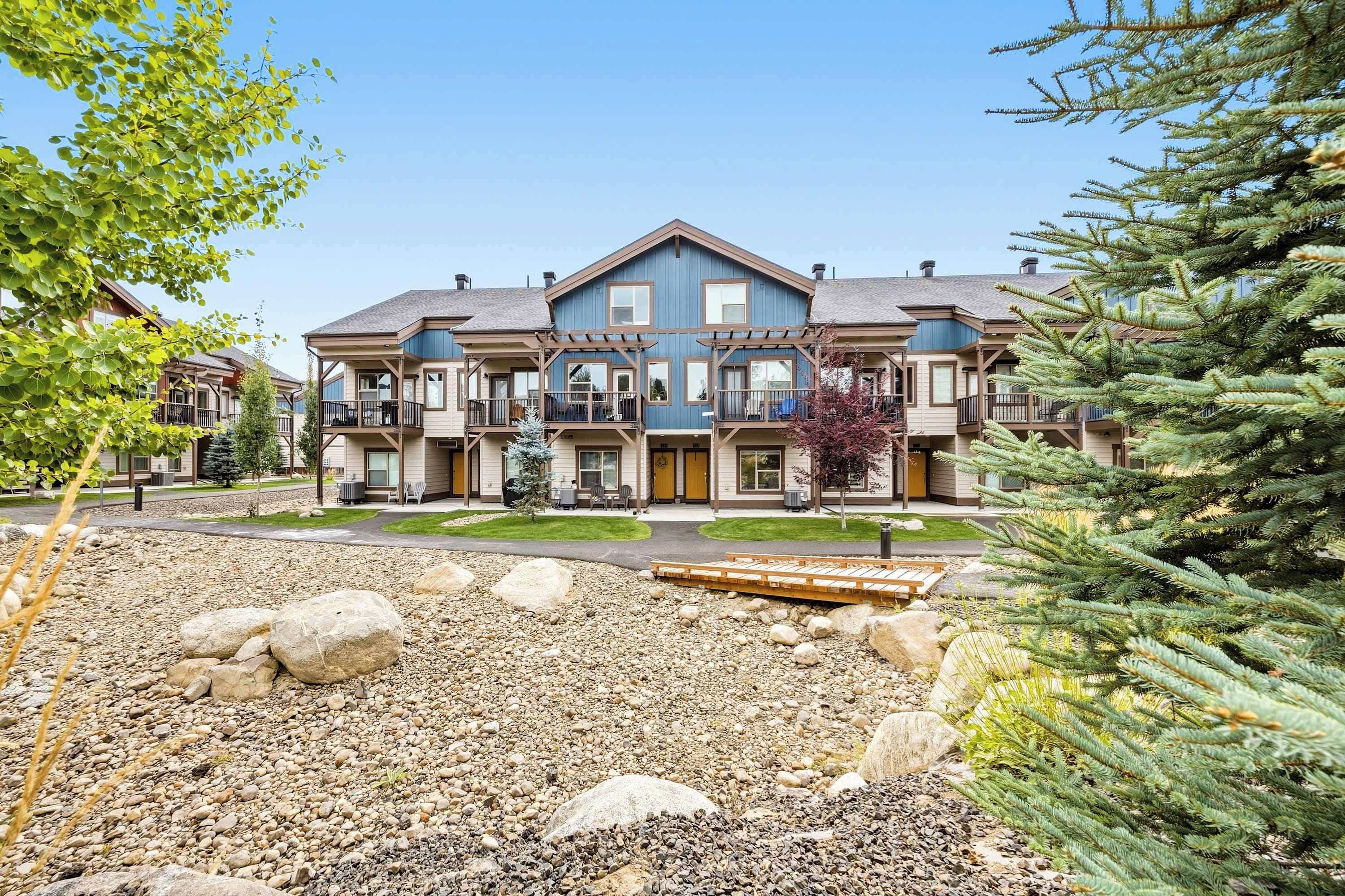 A multi-story building with balconies and a landscaped front yard.