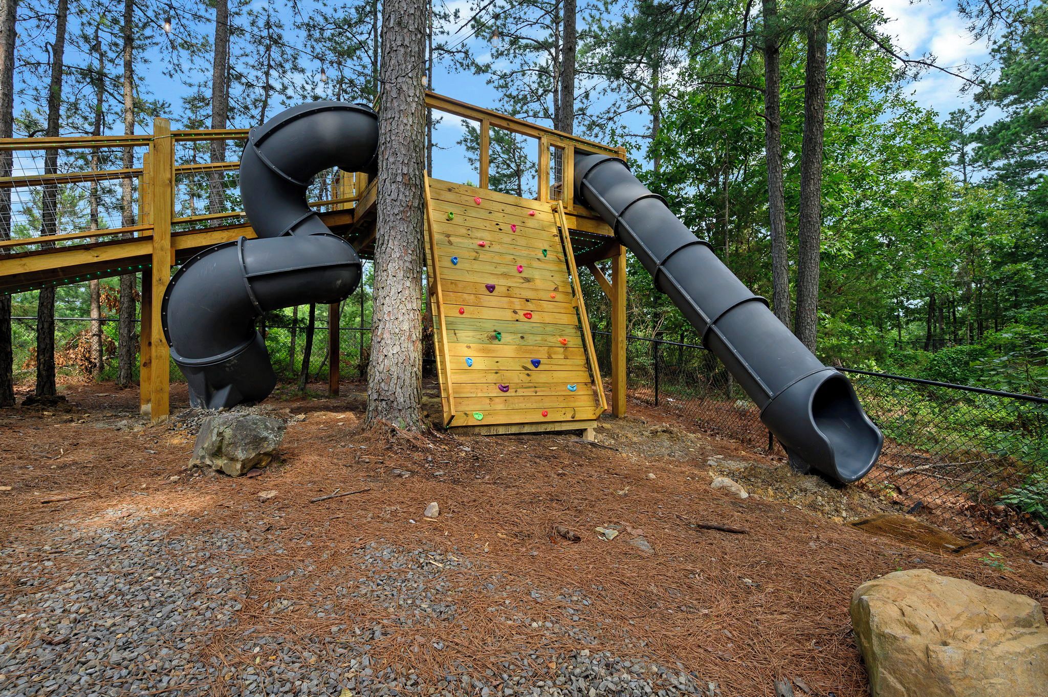 Ein Spielplatz mit Rutsche, Kletterwand und einer Holzterrasse.