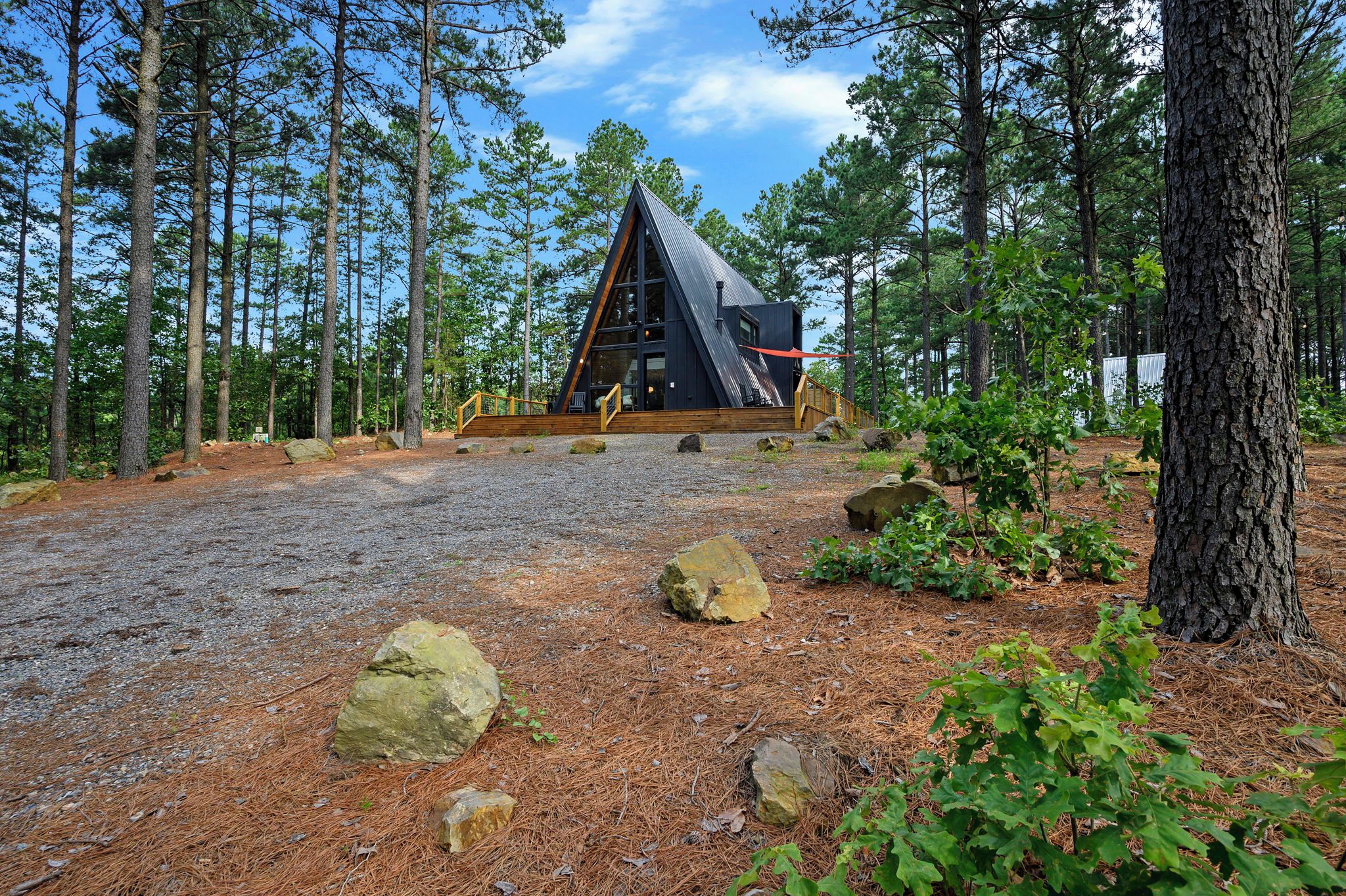 Eine Hütte mit einem dreieckigen Dach, umgeben von einem Wald mit Kiefern.