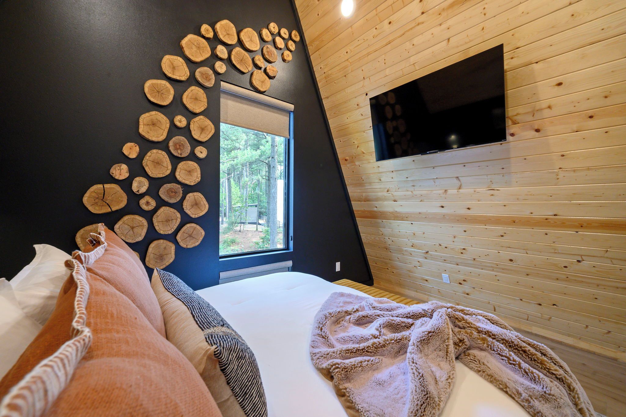 Ein Schlafzimmer mit einem Bett, Kissen, einem Fenster und einer Wand, die mit Holzschnitten verziert ist.