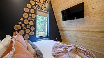 Ein Schlafzimmer mit einem Bett, Kissen, einem Fenster und einer Wand, die mit Holzschnitten verziert ist.