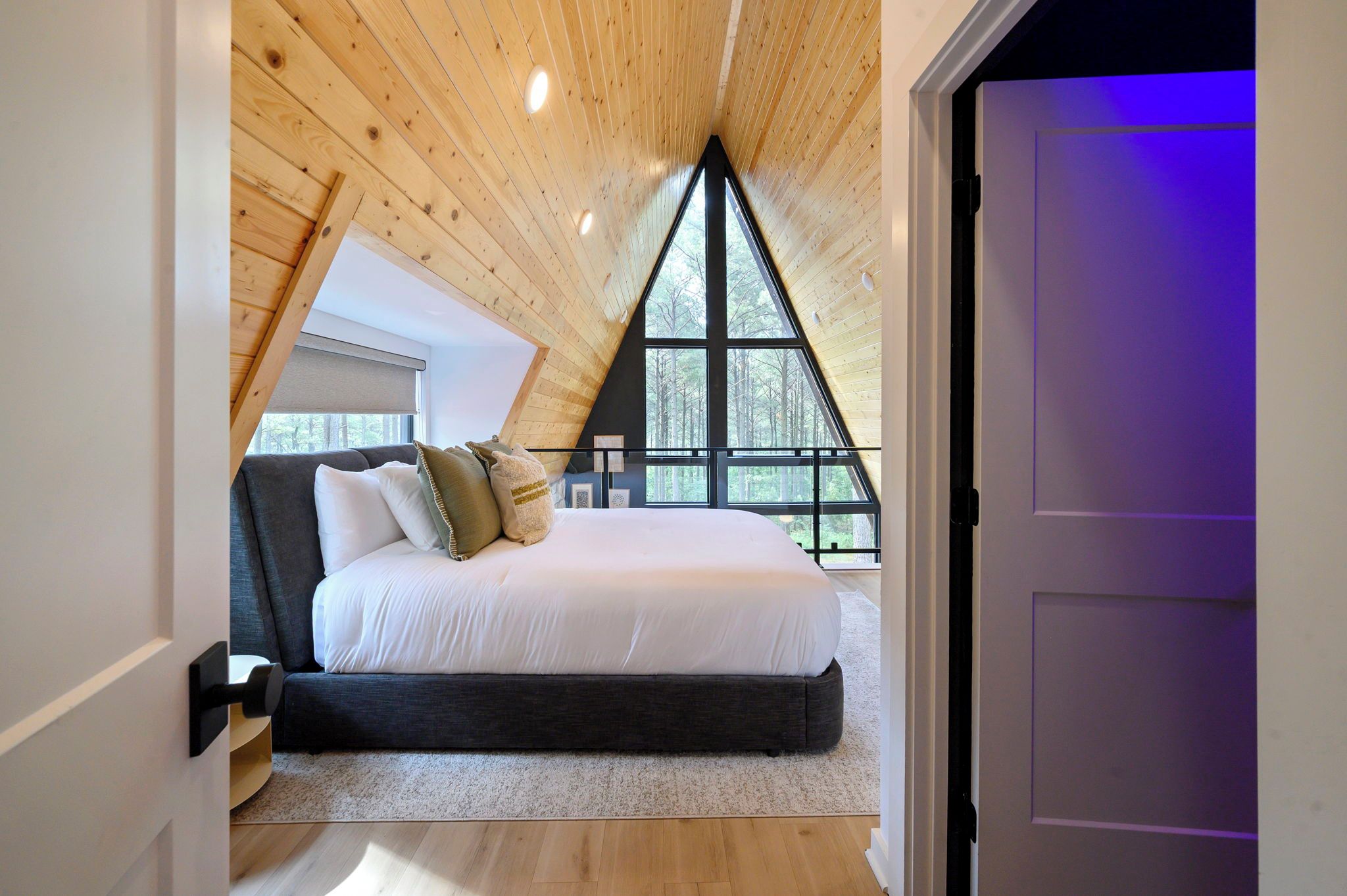 A bedroom with a sloped ceiling, a bed, and a large window.
