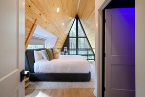 A bedroom with a sloped ceiling, a bed, and a large window. - Pine + Peak • Luxury A-Frame • Adventure Zone • Hot Tub (Broken Bow)