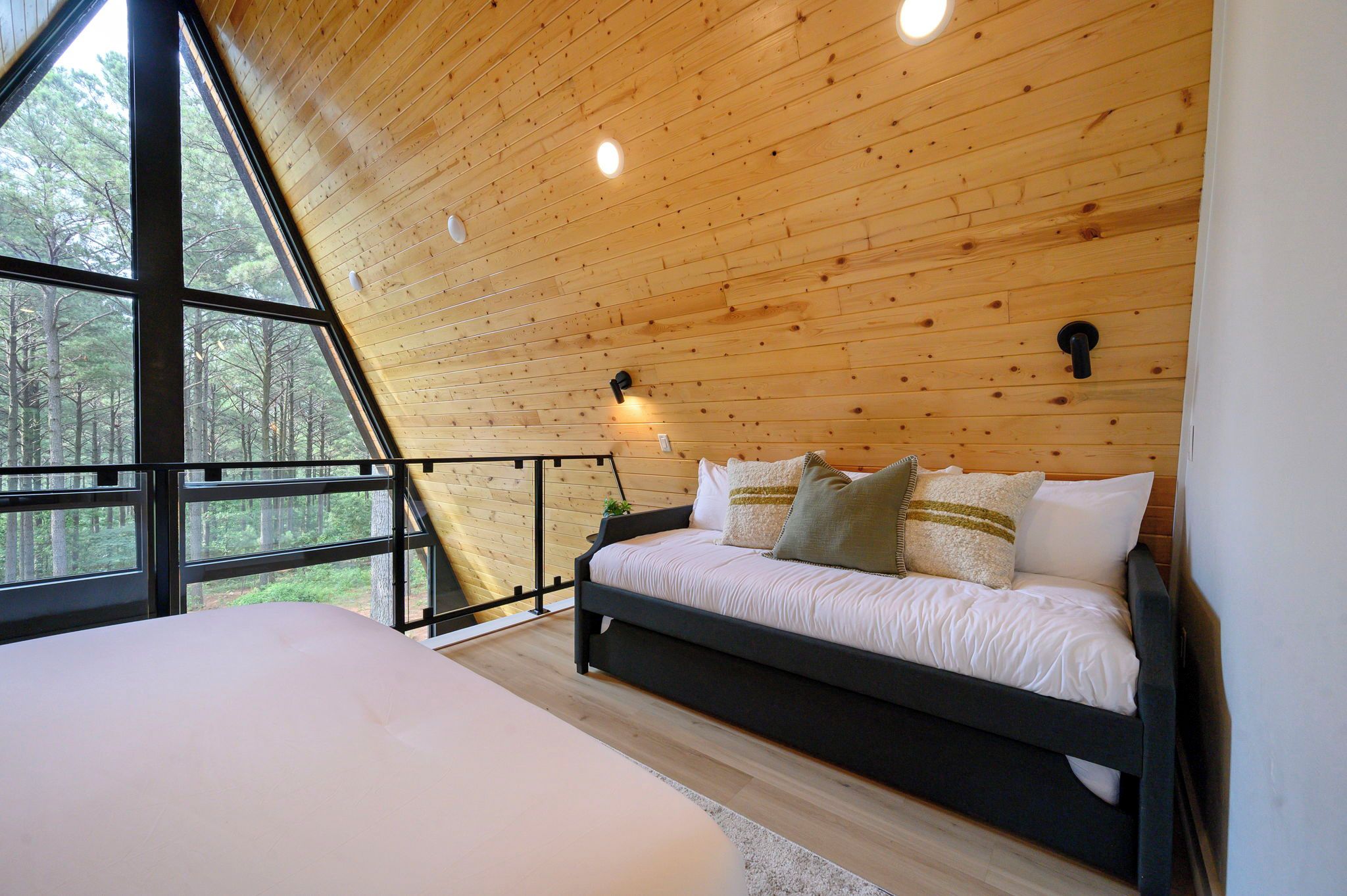 A bedroom with a bed, a window, and a wooden ceiling.