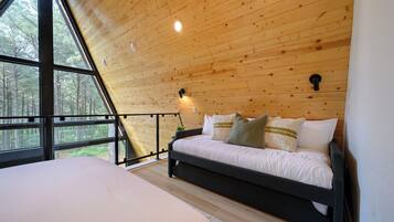 A bedroom with a bed, a window, and a wooden ceiling.