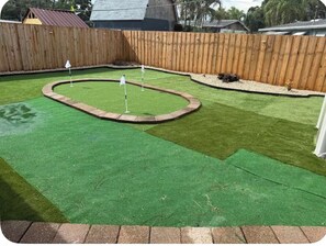 Ein Garten mit Kunstgrasanlage, Holzzaun und einem kleinen Gartenbereich.
