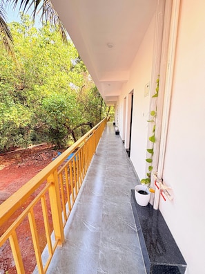 A corridor with a yellow railing, potted plants, and a view of greenery. - Room-friends Stay Studio R-9 1st Floor b (Arambol)