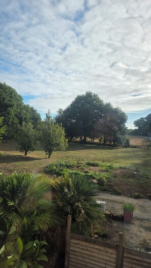 A grassy outdoor area with trees and a wooden fence. - Apartment in the countryside near the ocean. (Quéven)