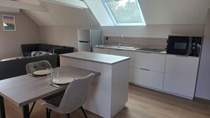 A compact kitchen with a dining area, a built-in oven, and a skylight. - Apartment in the countryside near the ocean. (Quéven)