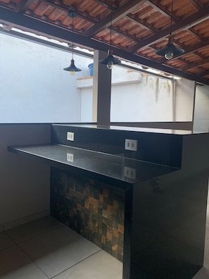 A kitchen with a black countertop, tiled backsplash, and pendant lights. - Complete, spacious, modern and cozy house. (Leopoldina)