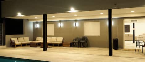 A covered outdoor area with a pool, seating, and a door leading to an interior space.