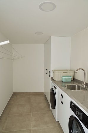 A compact laundry room with a washing machine, dryer, and a sink.
