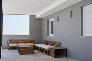 A modern room with a large window, a sofa, a bench, and a small table.