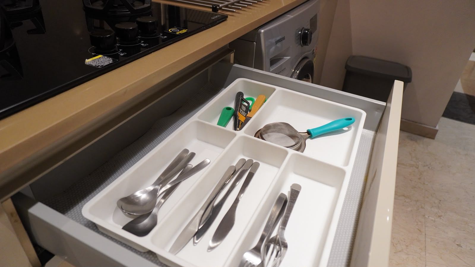 A kitchen drawer with utensils and a small appliance.