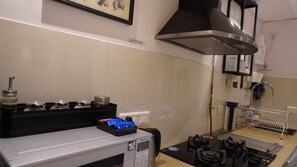 A kitchen with a gas stove, a microwave, a coffee maker, and a 'NO SMOKING' sign on the wall. - Egyptian Studio_Hiranandani Estate_Balcony (Thane)
