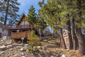 Eine Holzhütte mit einer Holzterrasse und einer Treppe, die zu einem Balkon führt.