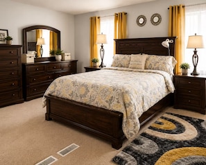 Un dormitorio con una cama grande, un aparador de madera oscura, dos mesitas de noche con lámparas, un espejo y una alfombra decorativa.