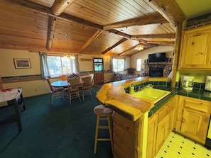 Ein rustikales Blockhaus-Interieur mit Essbereich, Küche und Kamin.