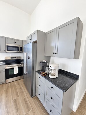A modern kitchen with grey cabinets, stainless steel appliances, and a black granite countertop. - Newly Listed -Canal front 2-bedroom Villa (Providenciales)