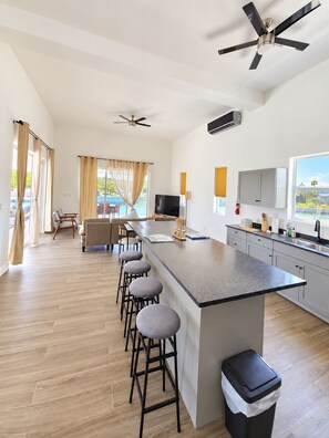 A modern kitchen with a central island, bar stools, and a ceiling fan. - Newly Listed -Canal front 2-bedroom Villa (Providenciales)