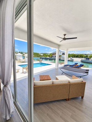 A modern outdoor living area with a pool, lounge chairs, and a view of a coastal landscape. - Newly Listed -Canal front 2-bedroom Villa (Providenciales)