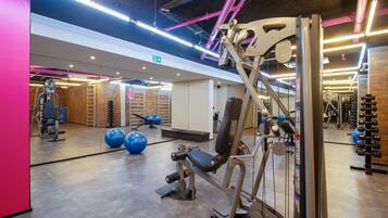 Une salle de sport équipée de matériel d’exercice, avec un miroir et un mur en briques.