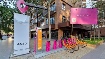 Un bâtiment moderne avec une grande enseigne rose bien visible, qui fait de la publicité pour « HOUZI SMART LIVING ».