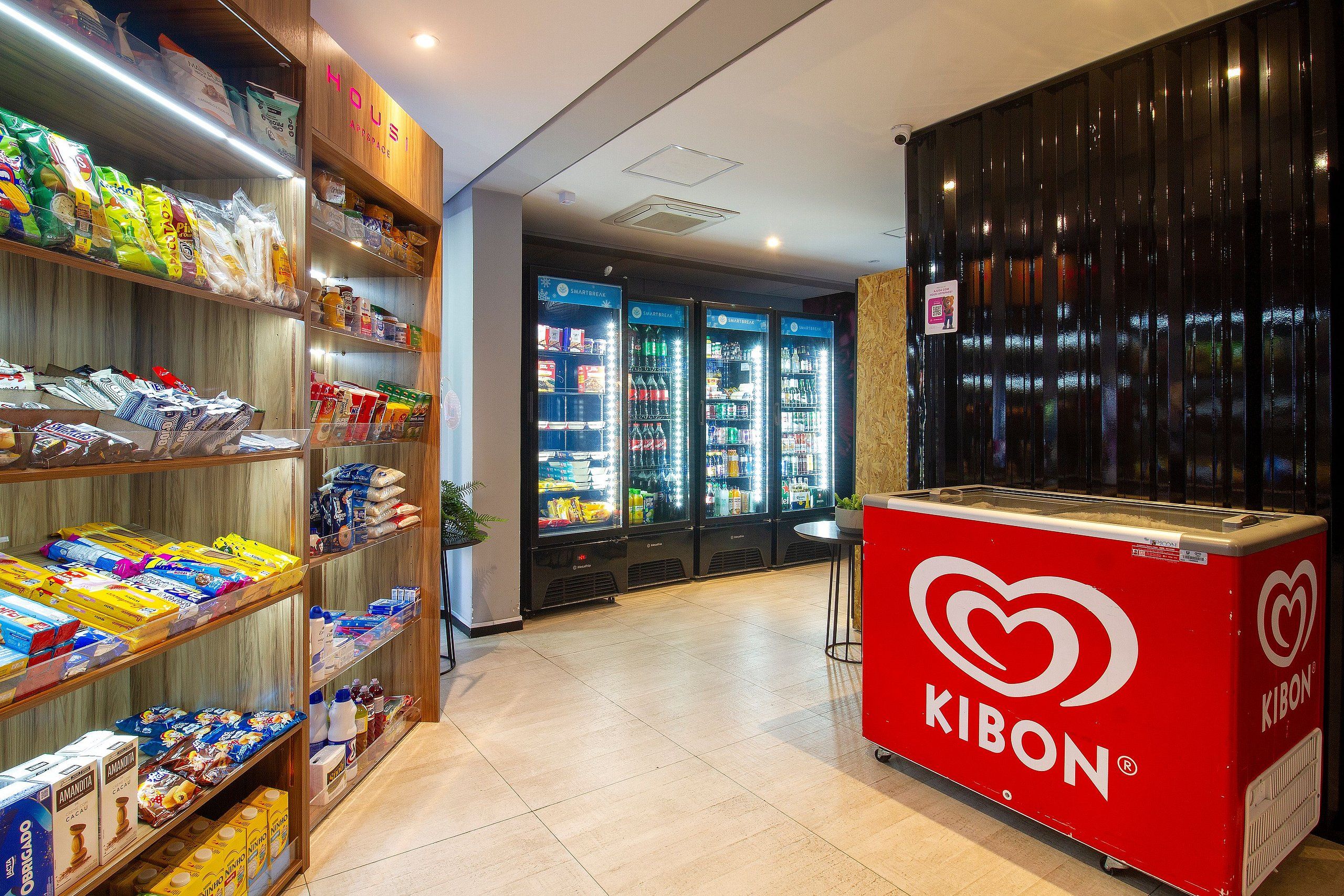 Interior de una tienda de comestibles con estantes repletos de diversos productos, un refrigerador de la marca Kibon y un enfriador de bebidas SmartBreak.