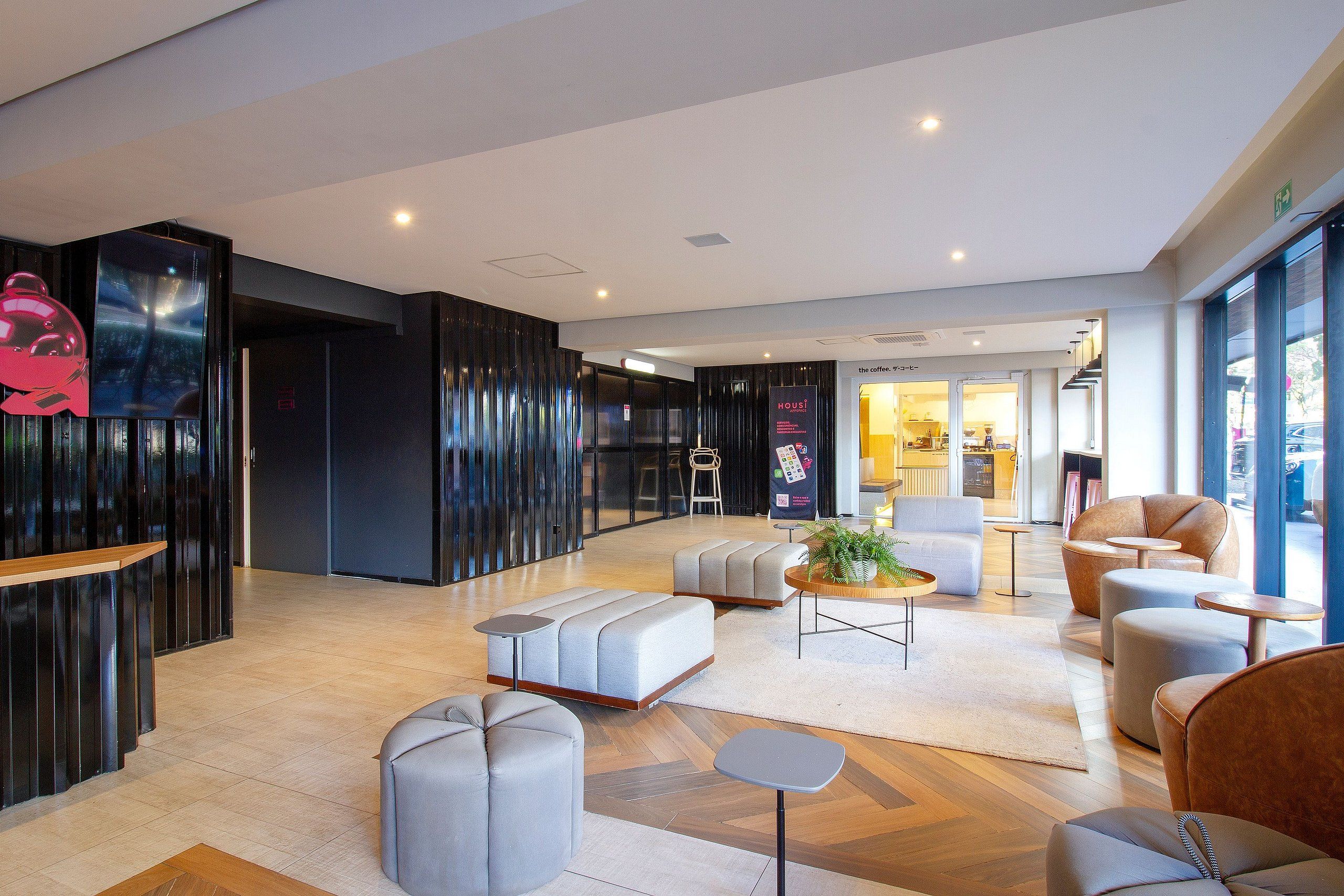 Un moderno vestíbulo de hotel con zonas de estar, un mostrador de recepción y una barra de café.
