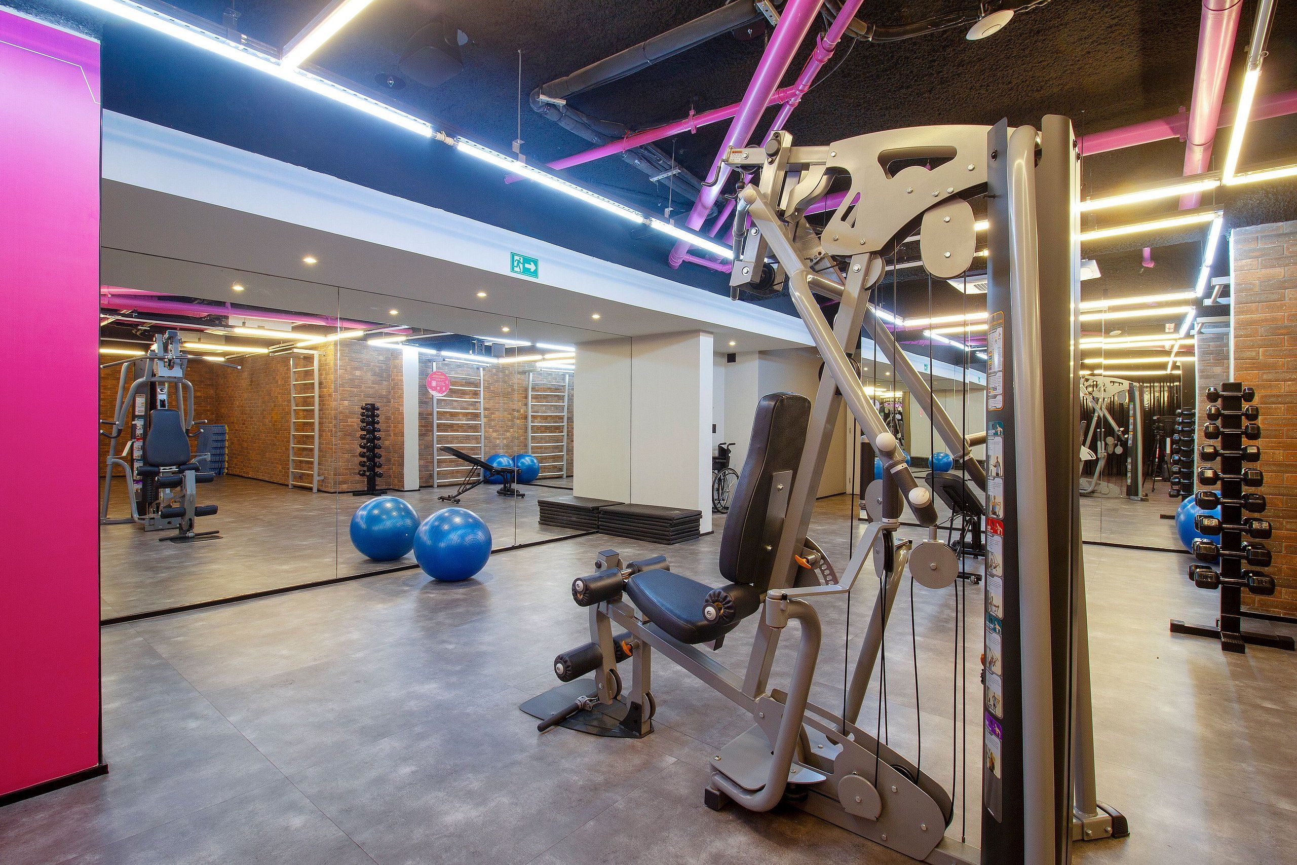 Un gimnasio con equipo de ejercicio, un espejo y una pared de ladrillo.