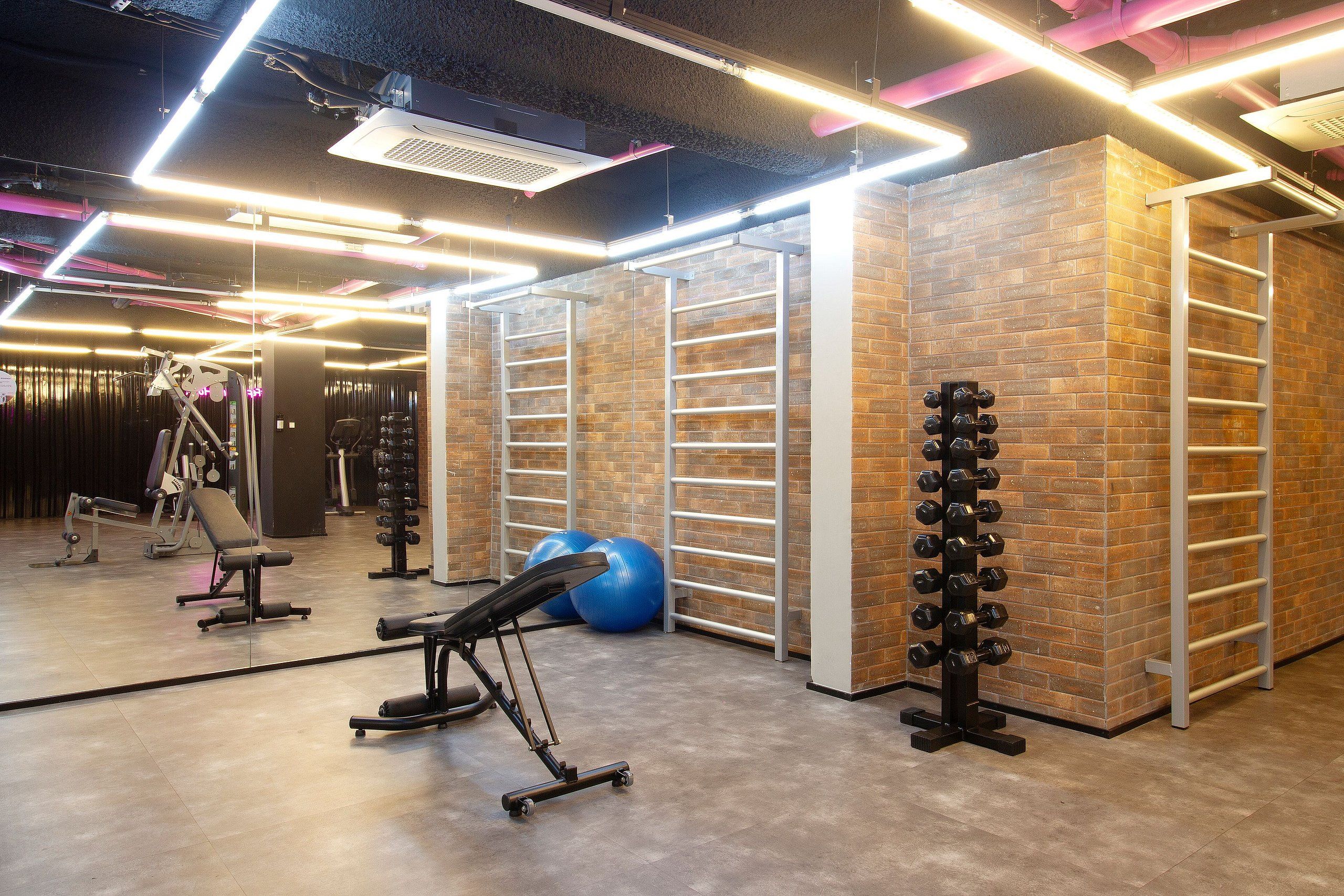 Un gimnasio con equipo de ejercicio, un estante de pared y una banca.