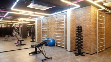 Une salle de sport équipée de matériel d’exercice, d’un porte-haltères fixé au mur et d’un banc.