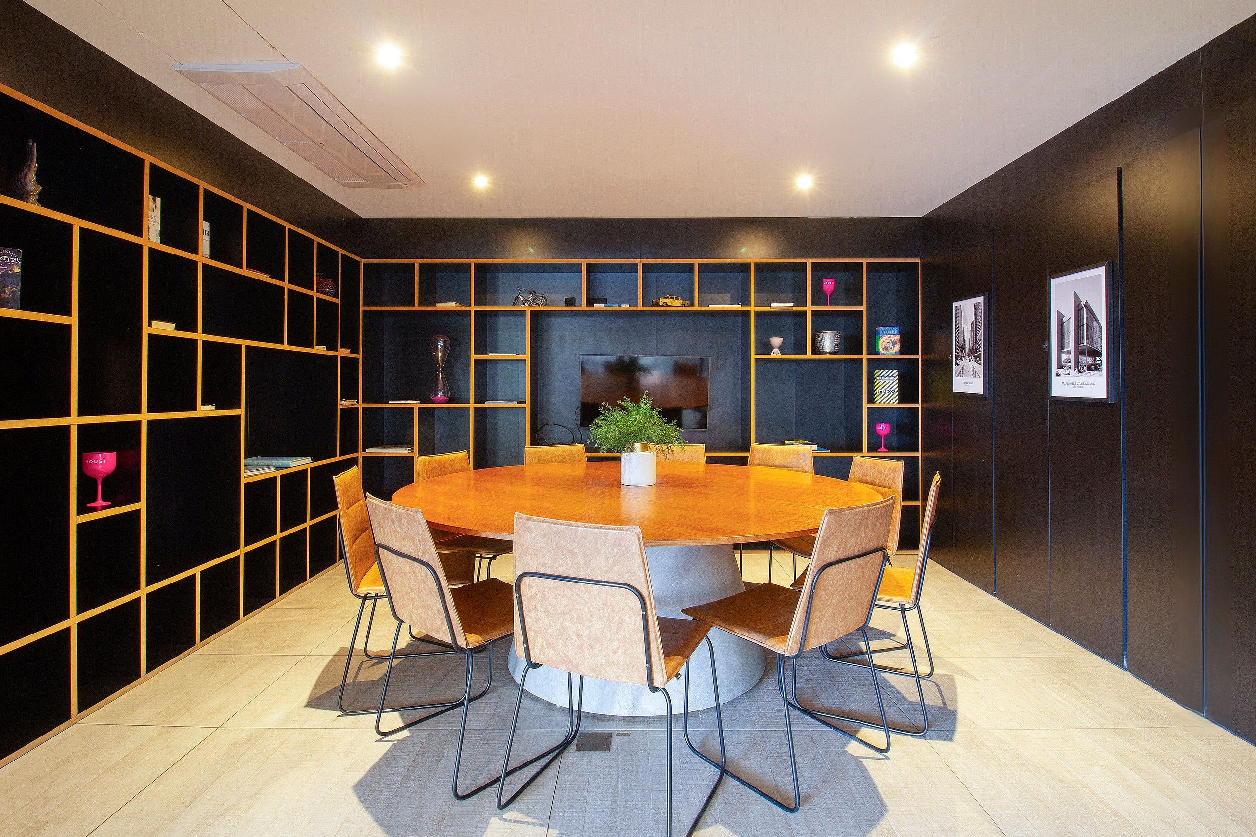 Un espace repas moderne avec une table ronde et des chaises, entouré d’étagères et d’objets décoratifs.