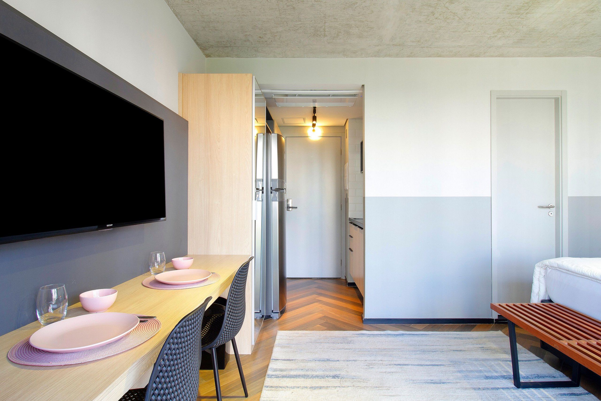 Eine moderne Küche mit Essbereich, einem an der Wand montierten Flachbildfernseher und einer Bank.