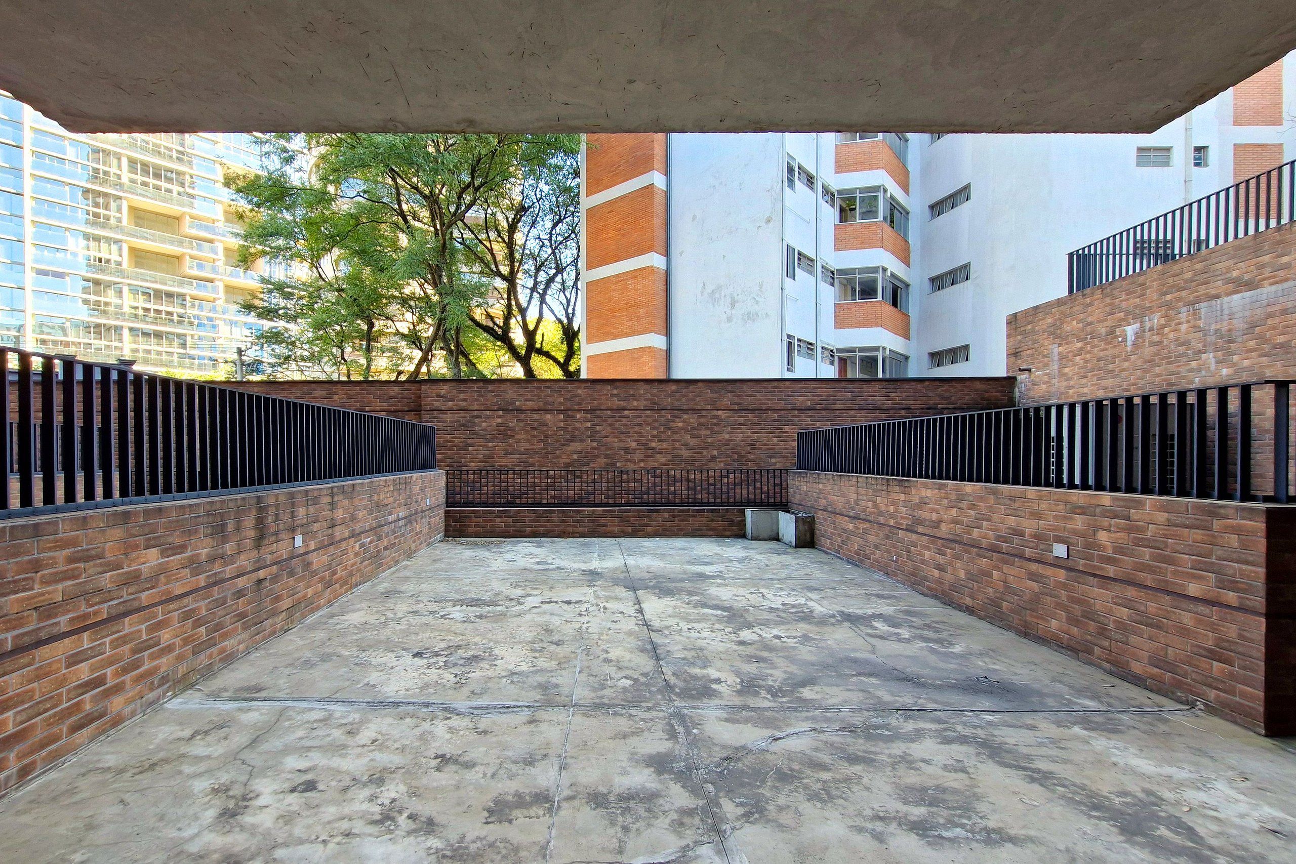 Une cour bordée de murs en briques et dotée d’un sol en béton, entourée d’immeubles.