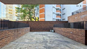 Un patio con muros de ladrillo y suelo de hormigón, rodeado de edificios.