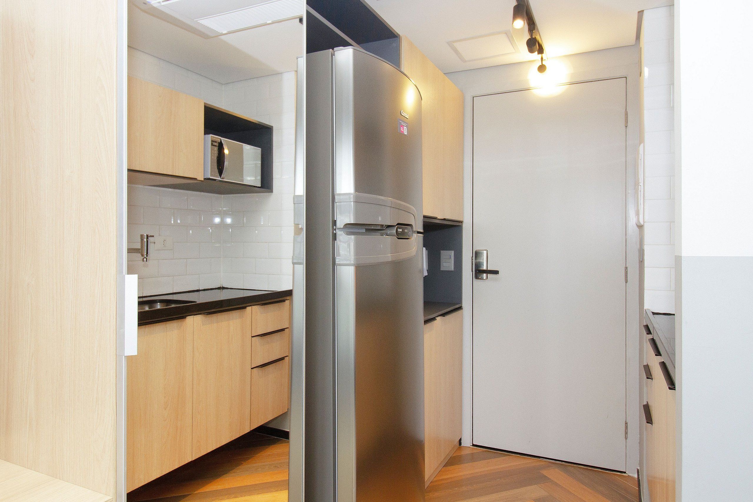 Eine moderne Küche mit einem Edelstahl-Kühlschrank, Holzschränken und einer schwarzen Arbeitsplatte.