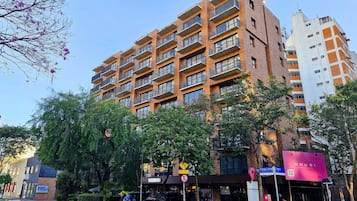 Un immeuble à plusieurs étages doté de balcons, un panneau de signalisation indiquant une limite de vitesse de 50 km/h, et une enseigne pour une entreprise nommée « HOUSI SMART LIVING ».
