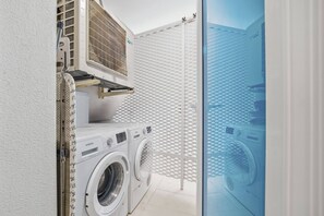 A laundry area with a washing machine and dryer, a ventilation unit, and a glass door leading to an outdoor area. - Panoramic View by IIM (Benalmádena)