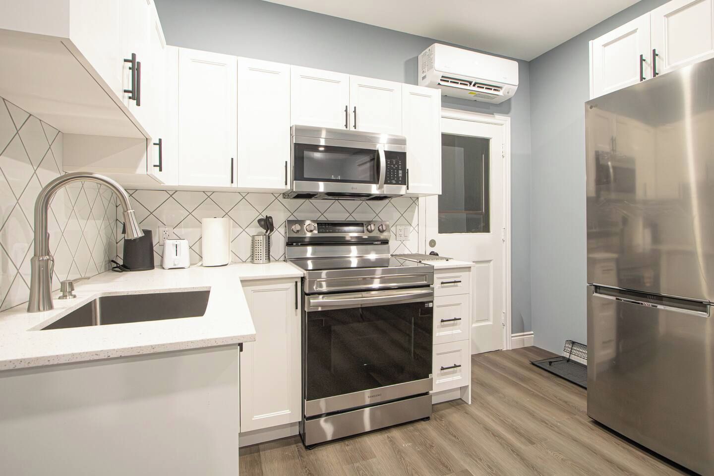 Una cocina moderna con armarios blancos, electrodomésticos de acero inoxidable y un salpicadero de azulejos.