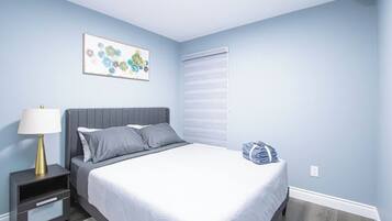 Una camera da letto con un letto, un comodino, una lampada e un'opera d'arte appesa al muro.