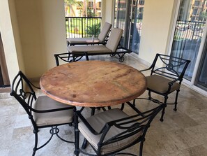 Une table ronde avec quatre chaises, une bouteille et un verre posés sur la table.