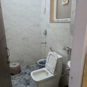 Un baño con inodoro, bidé y un lavamanos pequeño.