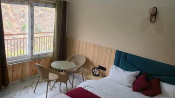 Ein Hotelzimmer mit Bett, kleinem Tisch mit Stühlen, Fenster mit Aussicht und Klimaanlage.