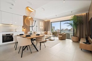 A modern living room with a dining area, large windows, and a view of the city. - Golden View by IIM (AN)