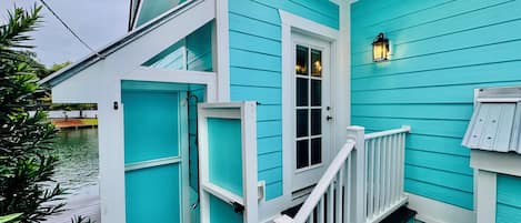 A turquoise building with a white door and a small porch.