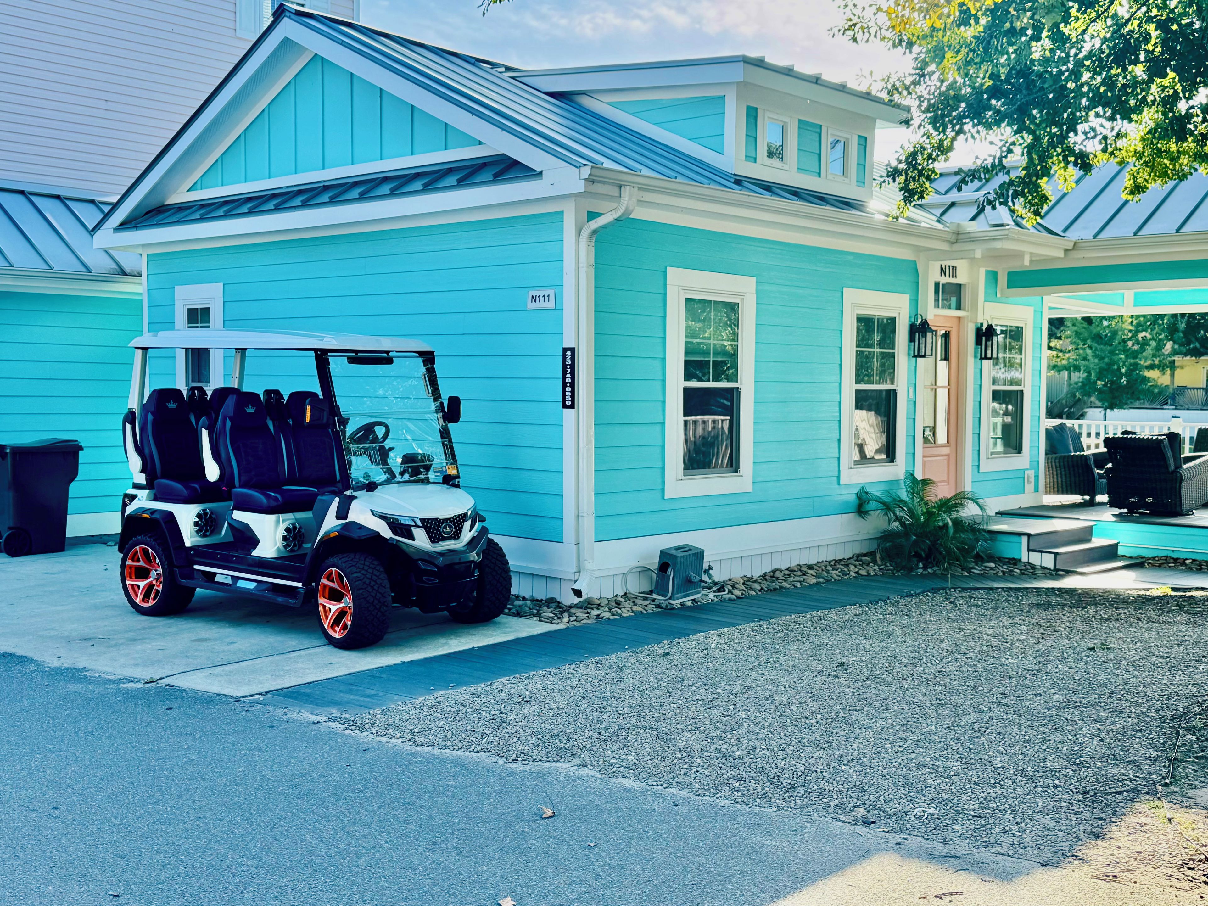 A light blue house with a covered porch and a golf cart parked in front.