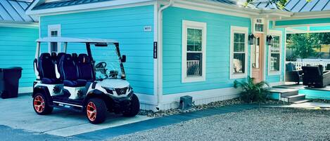 A light blue house with a covered porch and a golf cart parked in front.