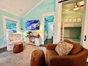 A living room with a sofa, armchair, and ottoman, a television, and a cabinet with decorative items. - Cozy Teal site N111 Ocean Lakes home close to everything Ocean Lakes! (Myrtle Beach)